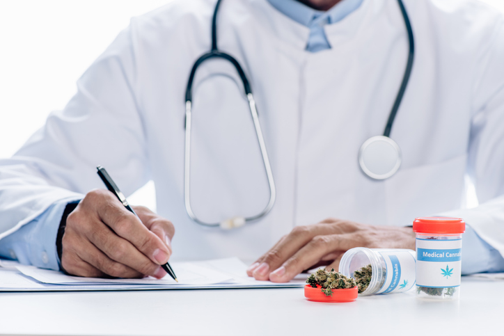 Doctor with cannabis next to him signing prescription for cannabis